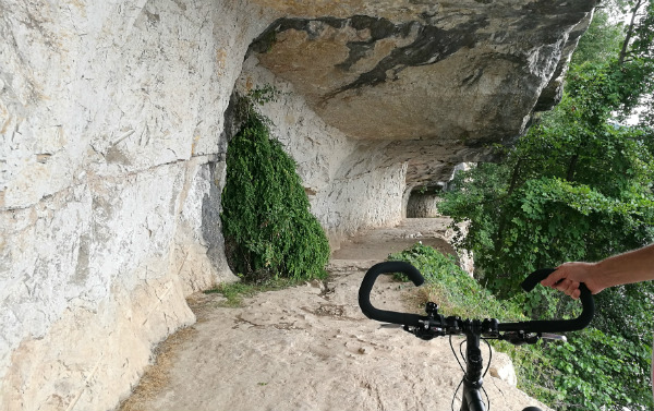 A tow path cut into rock with bike handles in foreground